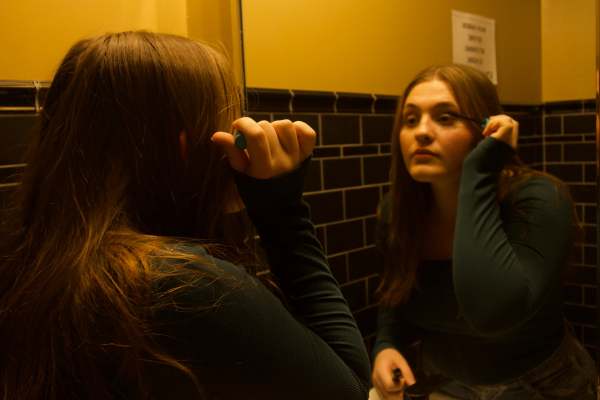 Woman looking in mirror applying mascara